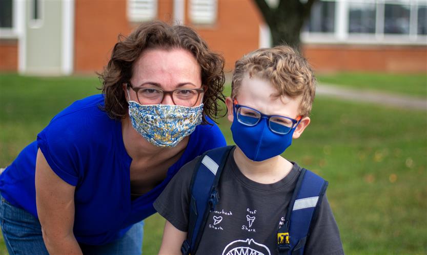 A woman and student smile while wearing masks